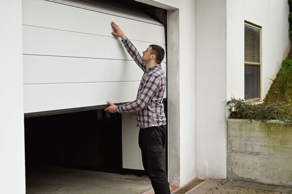 A man manually opening a white garage door in Seminole County, FL