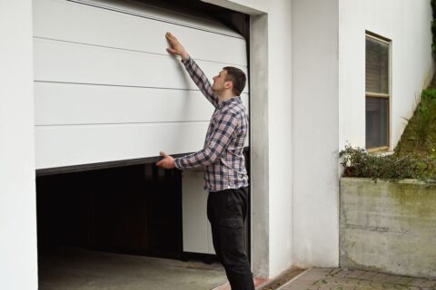 A man manually opening a white garage door in Seminole County, FL