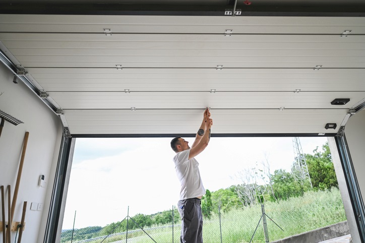 A man is fixing a garage door opener inside a residential garage in Seminole County, FL
