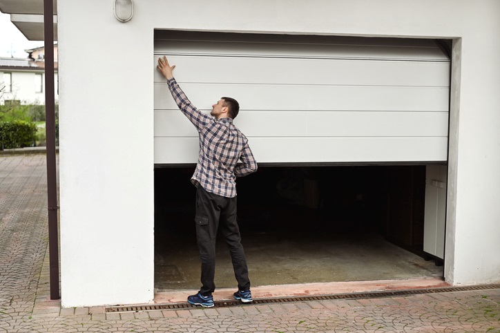 Man inspecting a partially open white garage door in Orlando & Central FL