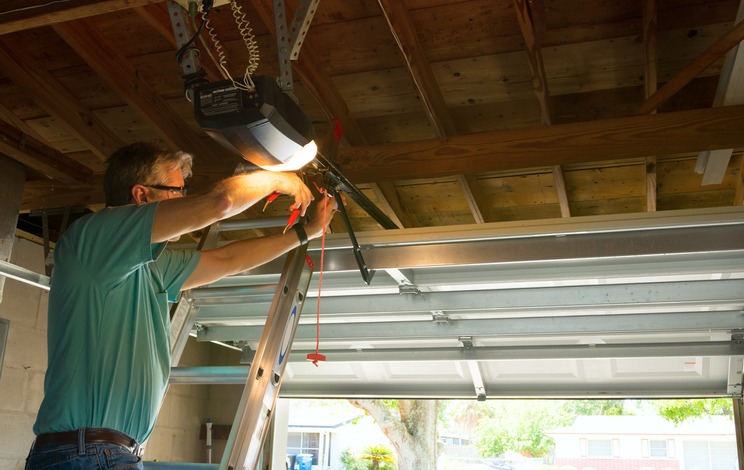 Man repairing garage door opener on ladder in Orlando & Central FL