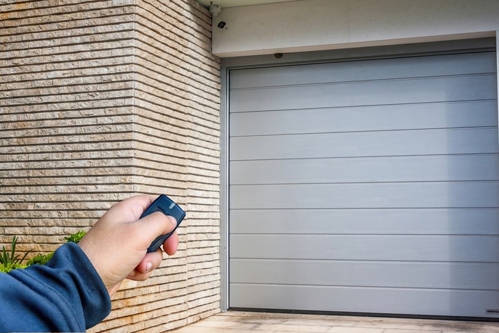 Hand using a remote to open a modern garage door in Orlando & Central FL