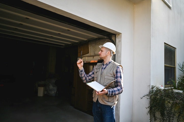 Licensed Contractor inspecting a residential garage exterior in Orlando & Central FL